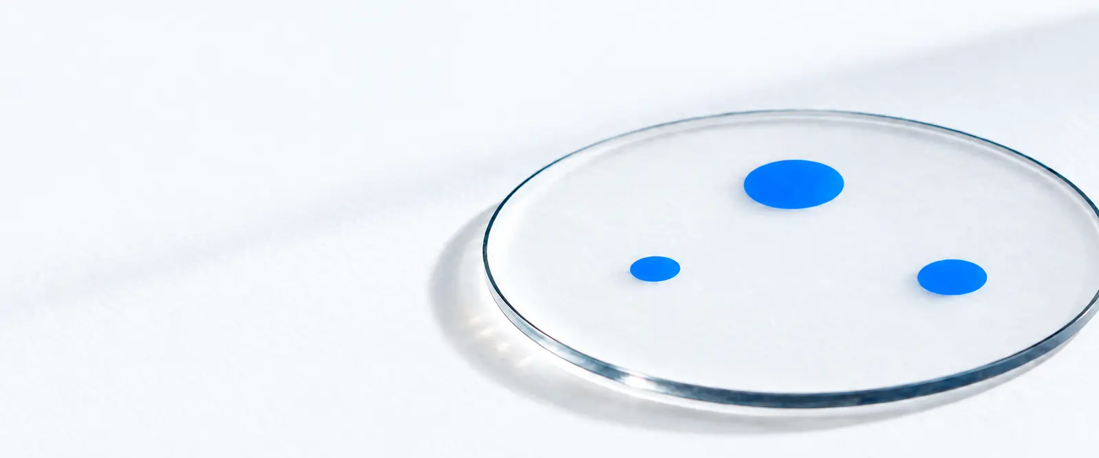 A clear glass calibration plate with three isolated blue points: a physical study of the Sky Link constellation.